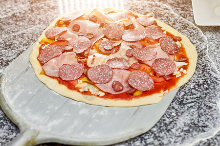 披萨皮上的未煮过的意大利腊肠披萨比萨皮从桌子上取下未图片