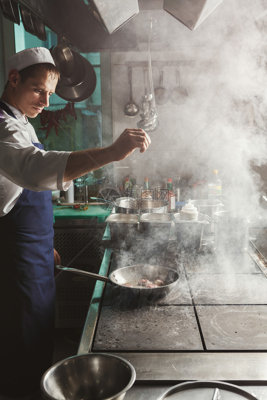 专业餐厅厨房男厨师在专业餐厅厨房烧烤和调味肉图片