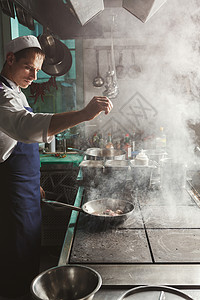 专业餐厅厨房男厨师在专业餐厅厨房烧烤和调味肉图片