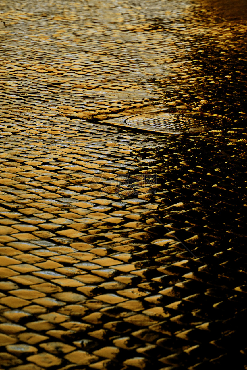 黄灯照亮的夜间潮湿的鹅卵石街道图片
