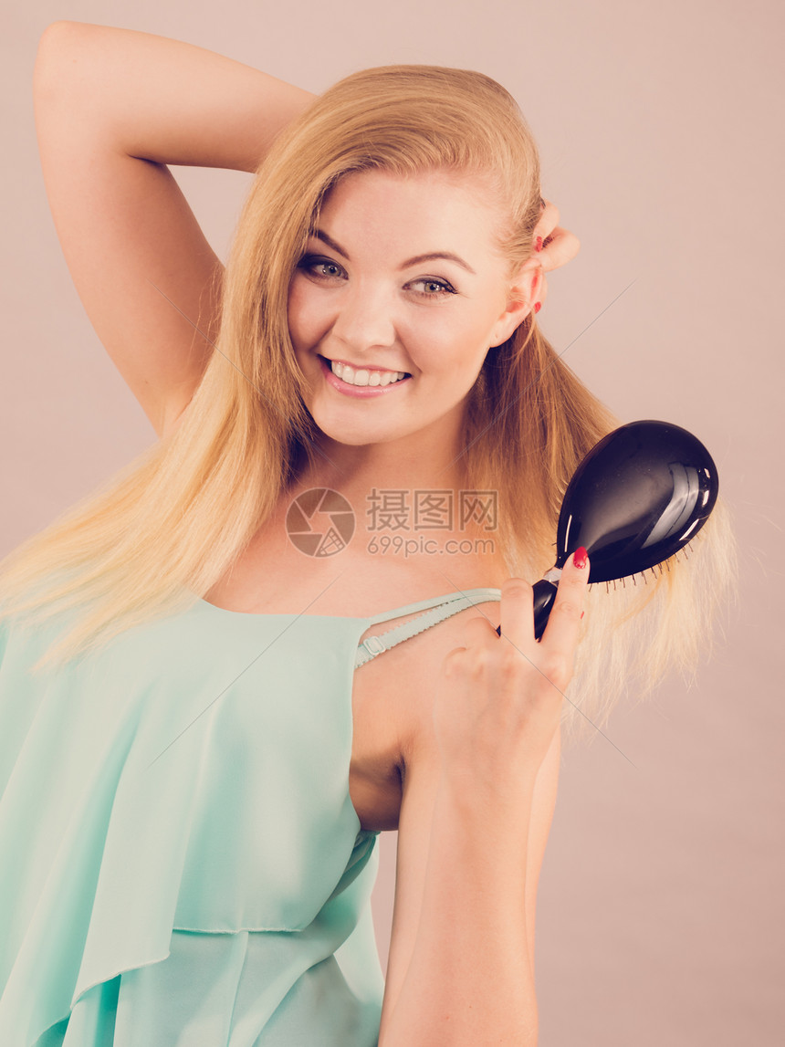 快乐的金发女人刷着她美丽的长的浅金色头发图片