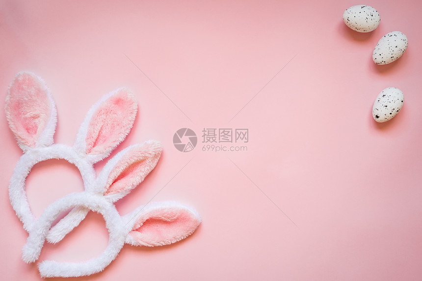 复活节鸡蛋和两只白毛兔子耳朵的顶端景色在粉红色背景图片