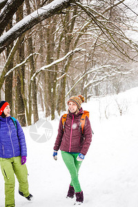 冬天在雪地里背着包在树林里旅行两个女孩穿过森林大笑两个朋图片