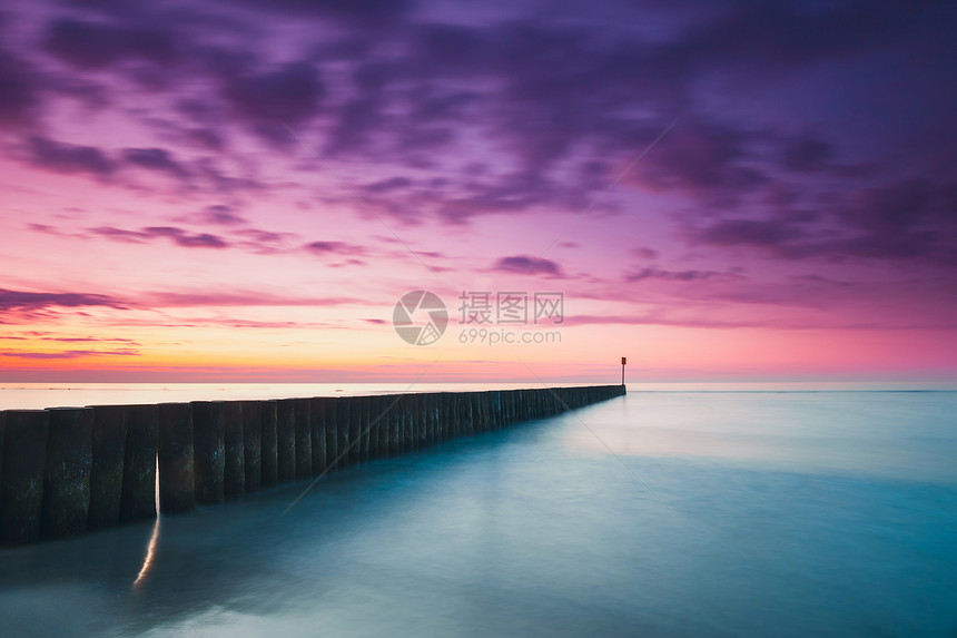 海滩上的日落带有木制防波堤紫色调图片