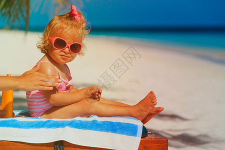 防晒妈在沙滩上给小女儿涂防晒霜图片