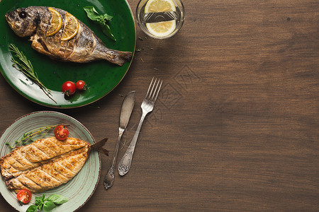 木制餐桌上的整条烤多拉鱼和白鱼图片