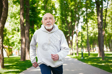 运动型老人晨练时在绿色公园跑步图片