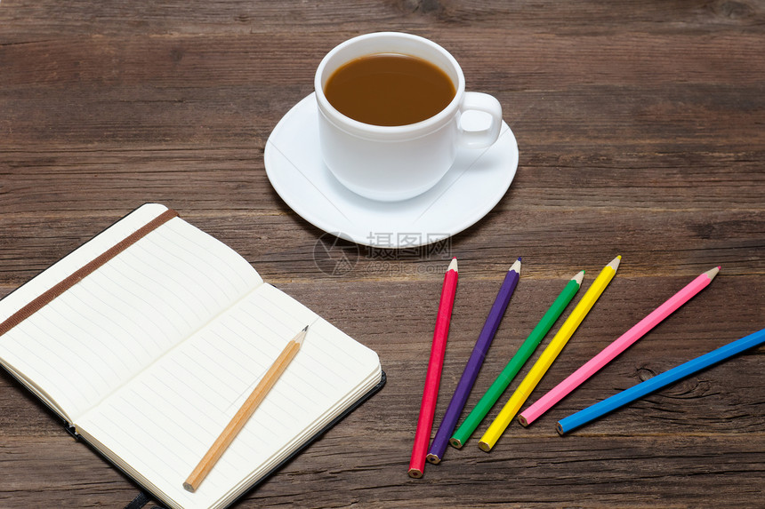 咖啡杯彩色铅笔和记本木制背景图片