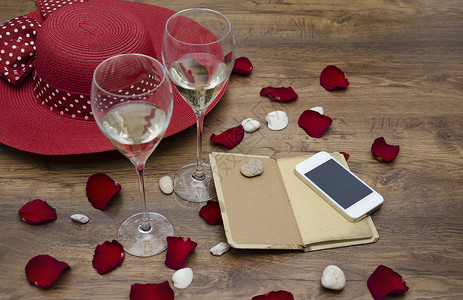 带记事本的手机带香槟的眼镜红帽子和红玫瑰花瓣图片