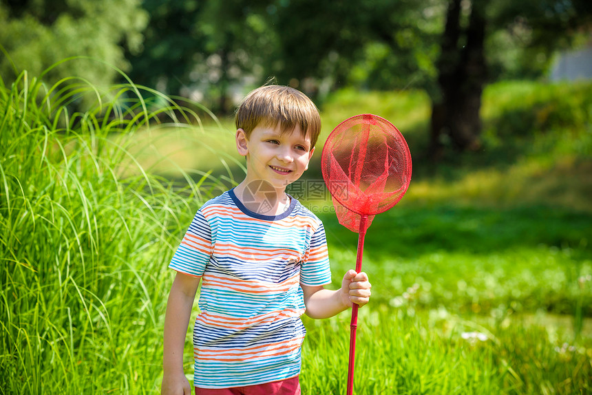 可爱的高加索孩子在温暖和阳光明媚的夏日或春日在草地上玩瓢网孩子们的积极休闲时间小男孩在寻找蝴蝶和虫子图片