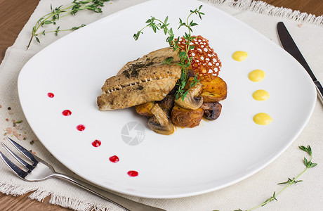 白盘上的土豆和蘑菇烤鱼图片