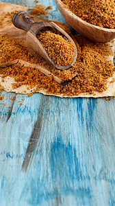 蓝色木桌上的棕色未精制蔗糖特写图片