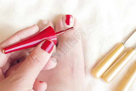 女人手拿着红刷指甲用红色涂她的手指图片