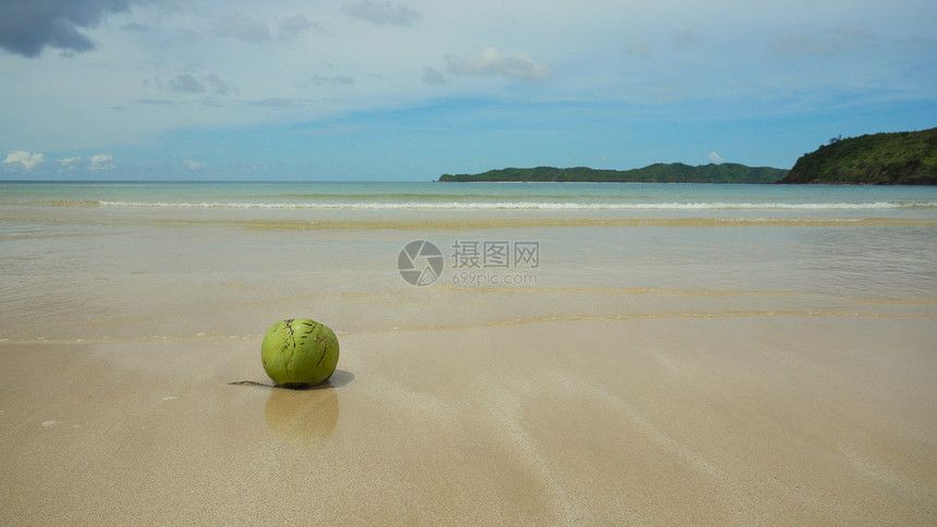 在蓝天大海云彩背景的热带海滩沙上的绿色椰子从棕榈的新鲜椰子在沙滩上热带海滩图片