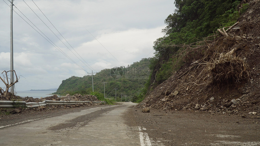 山体滑坡和山体滑坡泥土和岩石阻塞了道路被毁坏的农村道路滑坡在强大的洪水中受损倒在山上菲图片