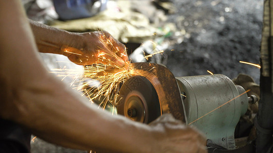 在铁匠铺的磨刀机上磨刀磨刀器和带刀片的手工人用磨石背景图片