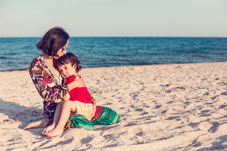 孩子和妈在海滩上男孩正在和他的妈玩耍孩子拥抱妈并微笑一个女人和她的儿图片