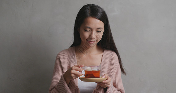 在灰色背景下喝茶的女人图片