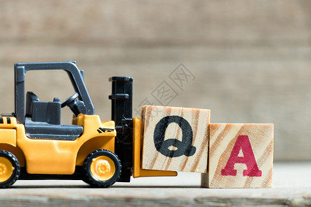 玩具黄色叉车持有字母块Q以完成单词QA图片