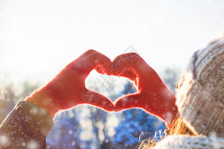 红手套中的女手在心脏形状中折叠冬图片