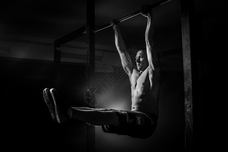 男人在十字栏上为手的肌肉做锻炼图片