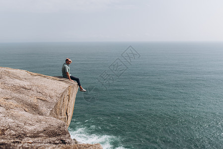 人类在悬崖边缘放松享受海图片