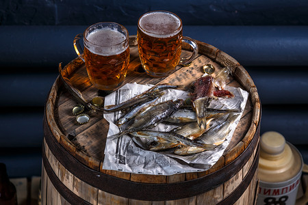 啤酒杯木桶上带干鱼的啤酒图片
