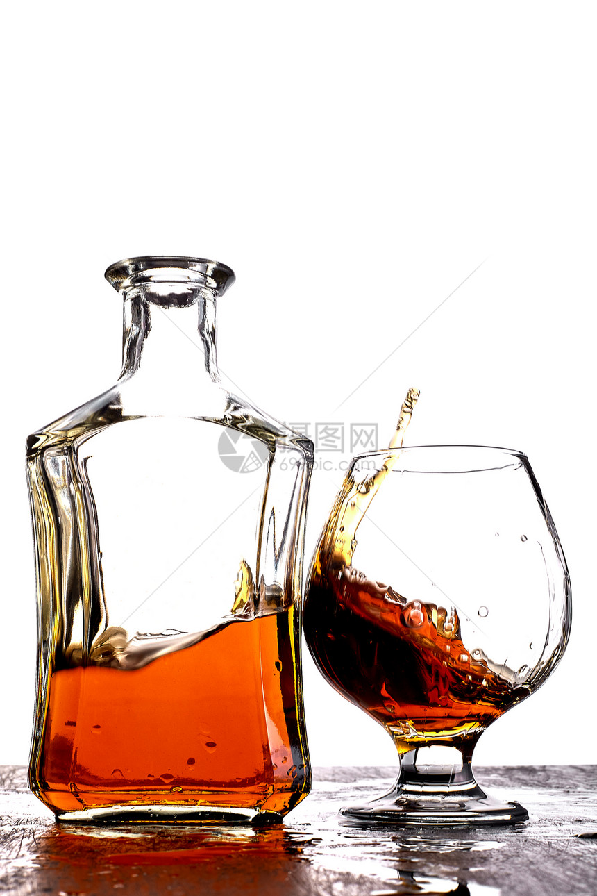 一杯泼溅威士忌桌上放着瓶子白色背光图片