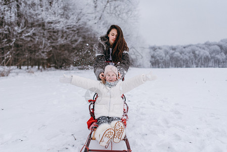 坐在雪橇上的小妹和大姐站图片