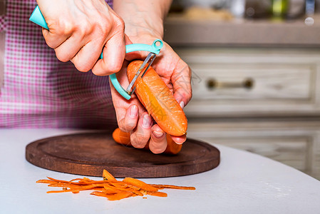 女手剥生胡萝卜煮汤的特写图像图片