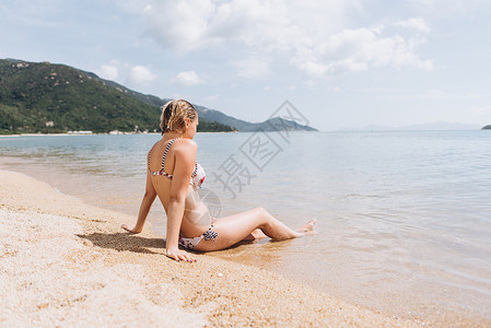 穿着比基尼坐在海边的女人的景色图片