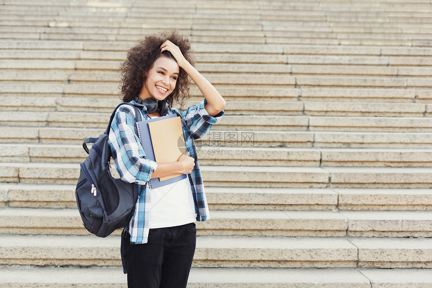 快乐微笑的非洲裔美国学生女孩背着包在大学台阶背景图片