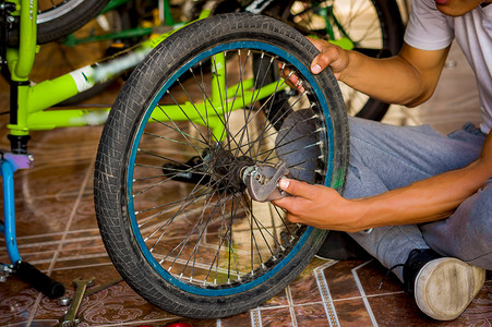 关闭自行车机械师使用扳手和修理车轮在车间图片