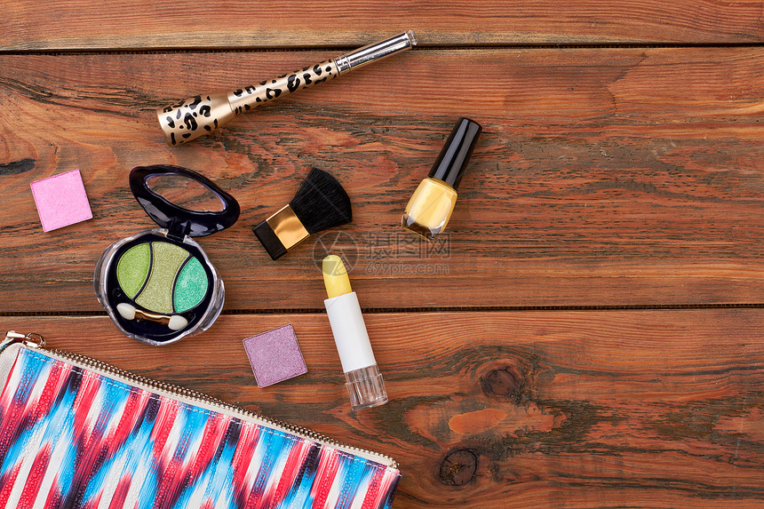 与化妆品的木制背景粉红色的化妆包和棕色背景的不同化妆品图片