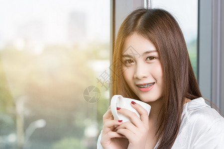 美丽的亚洲女人早上愉快地喝咖啡图片