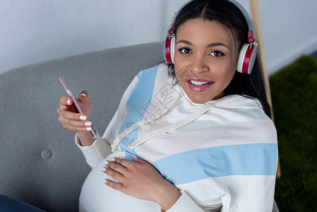 带着耳机和智能手机听音乐的非洲孕妇图片