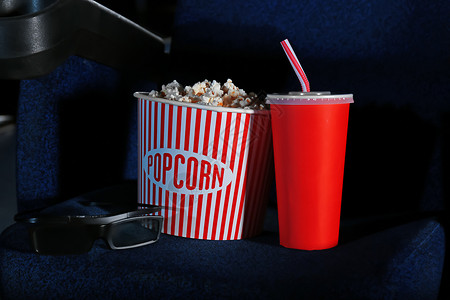 电影院椅子上放着美味爆米花和可乐的桶图片