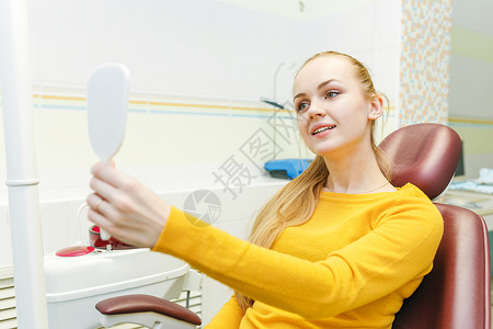 在口腔诊所接受牙科治疗后年轻女在镜背景图片