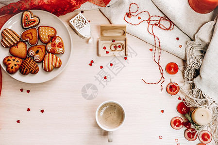 用杯子和饮料装饰心形饼干红丝带蜡烛线金色结婚戒指和背景上的红图片