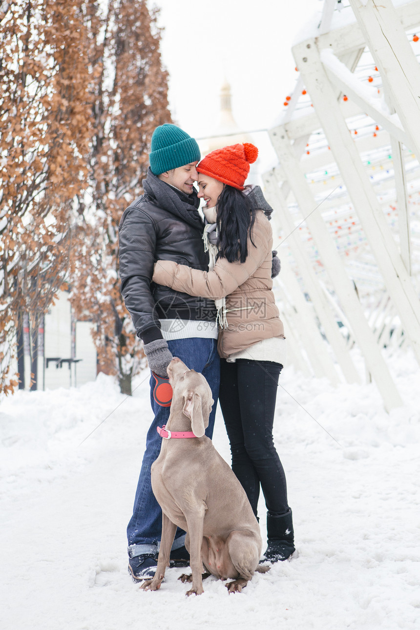 和他们的小狗一起在雪天散步图片