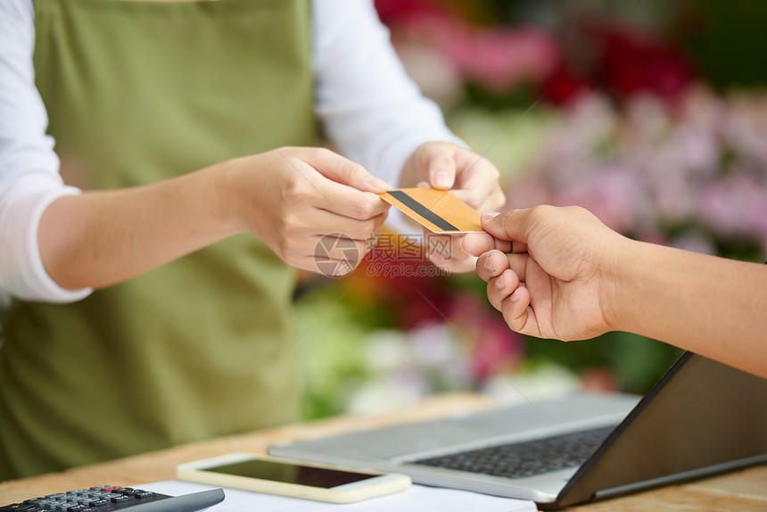 无法识别的客户在花卉店用信卡支付购货费的近镜头图片