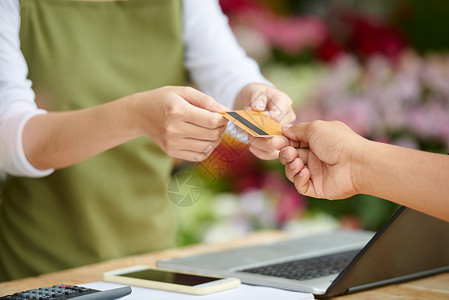 无法识别的客户在花卉店用信卡支付购货费的近镜头背景图片