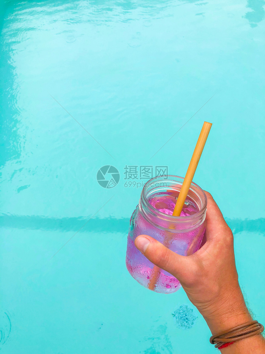 粉红饮料在一个透明的玻璃杯中用木根稻草在池底和白色背景上装着木干侧视图图片