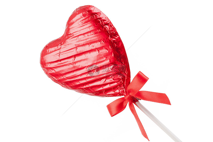 红巧克力爱心棒糖和一根棍子上的红丝结弓在白色背景图片
