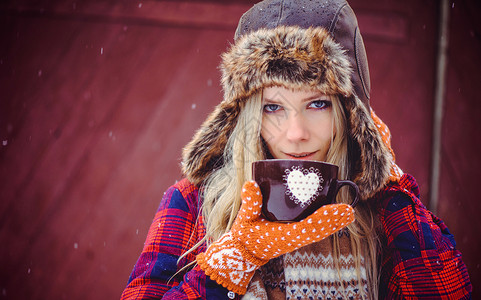 穿着冬帽和华莱士的温柔女人喝着一杯热茶或红底咖啡一部图片