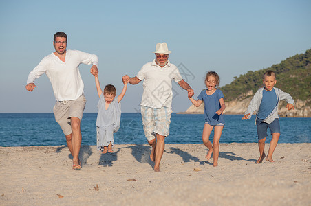 五三代幸福家庭沿着海滩奔跑图片