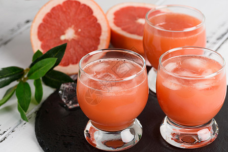 木制背景上的葡萄柚汁和成熟的葡萄柚图片