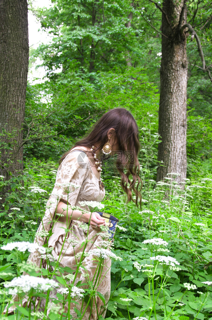 穿着复古长裙的女人走进高的草丛中背图片