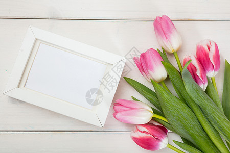 粉红郁金香花束和白木背景的白色空白框复图片