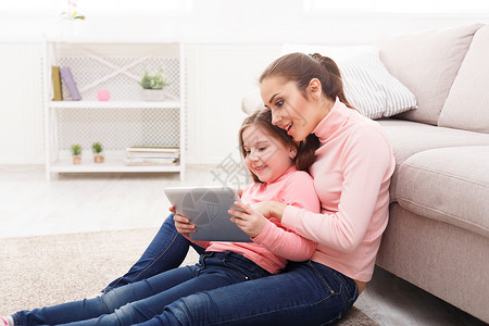 快乐的女孩和她妈在家中使用平板电脑坐在地板上母亲节关系母共同活动和兴趣信任支持爱抚母温背景图片